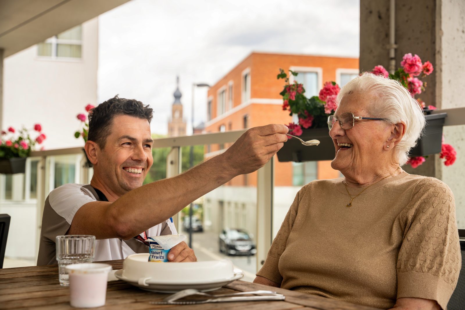 Zorgverlener die een oudere vrouw helpt bij het eten op een terras